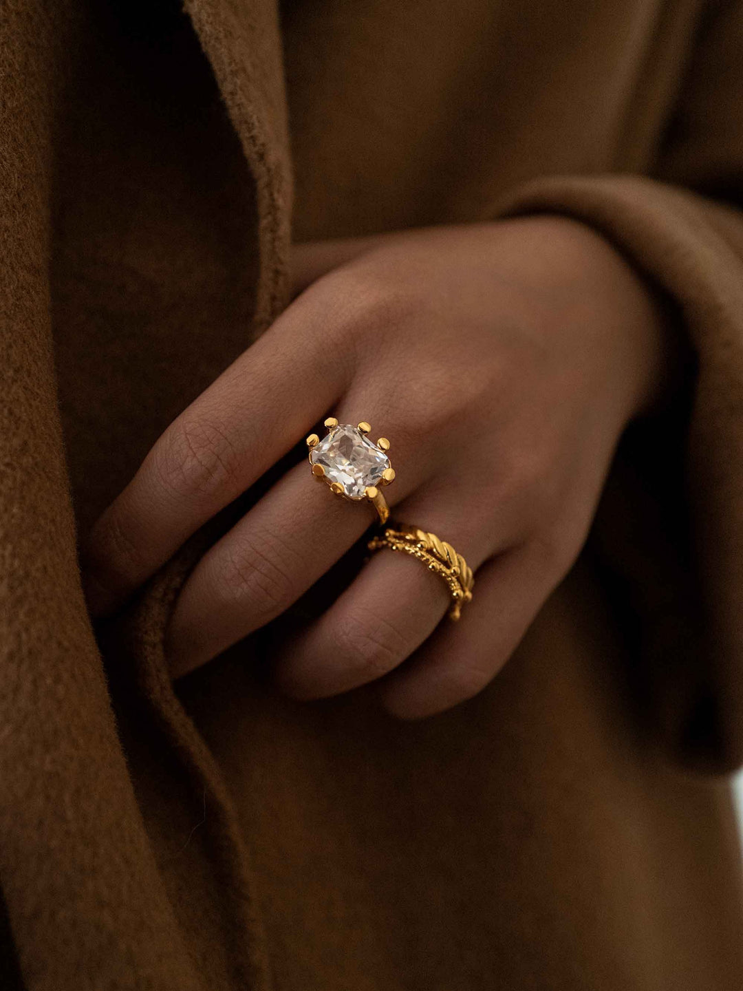 a hand wear A gold ring with a square glass crystal