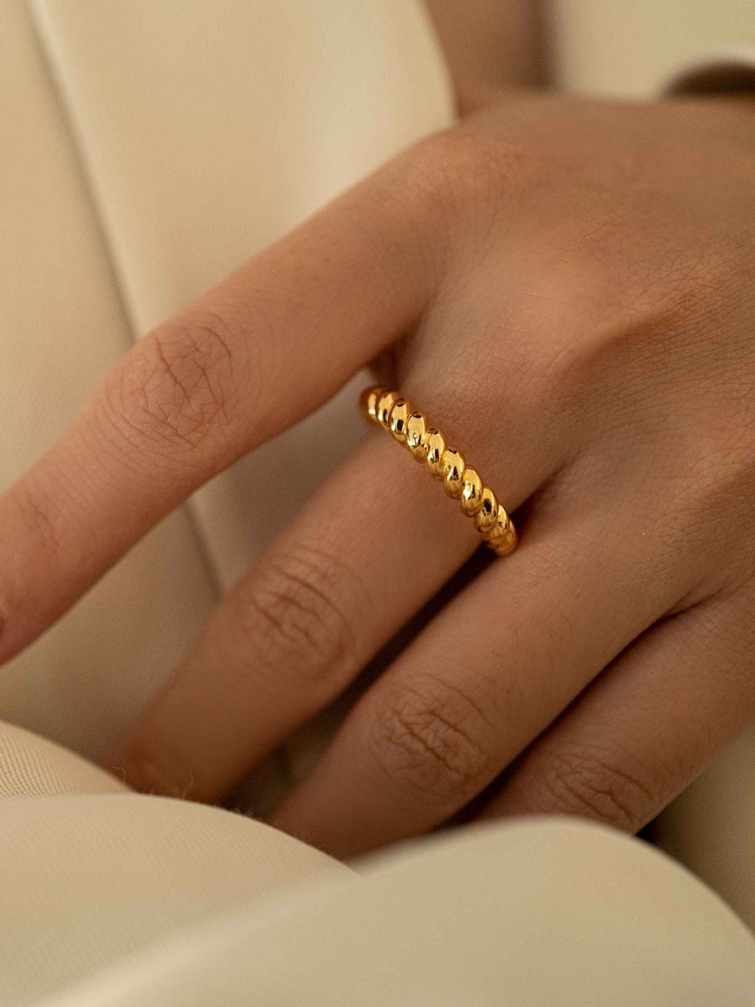 a hand wear A gold twist ring.