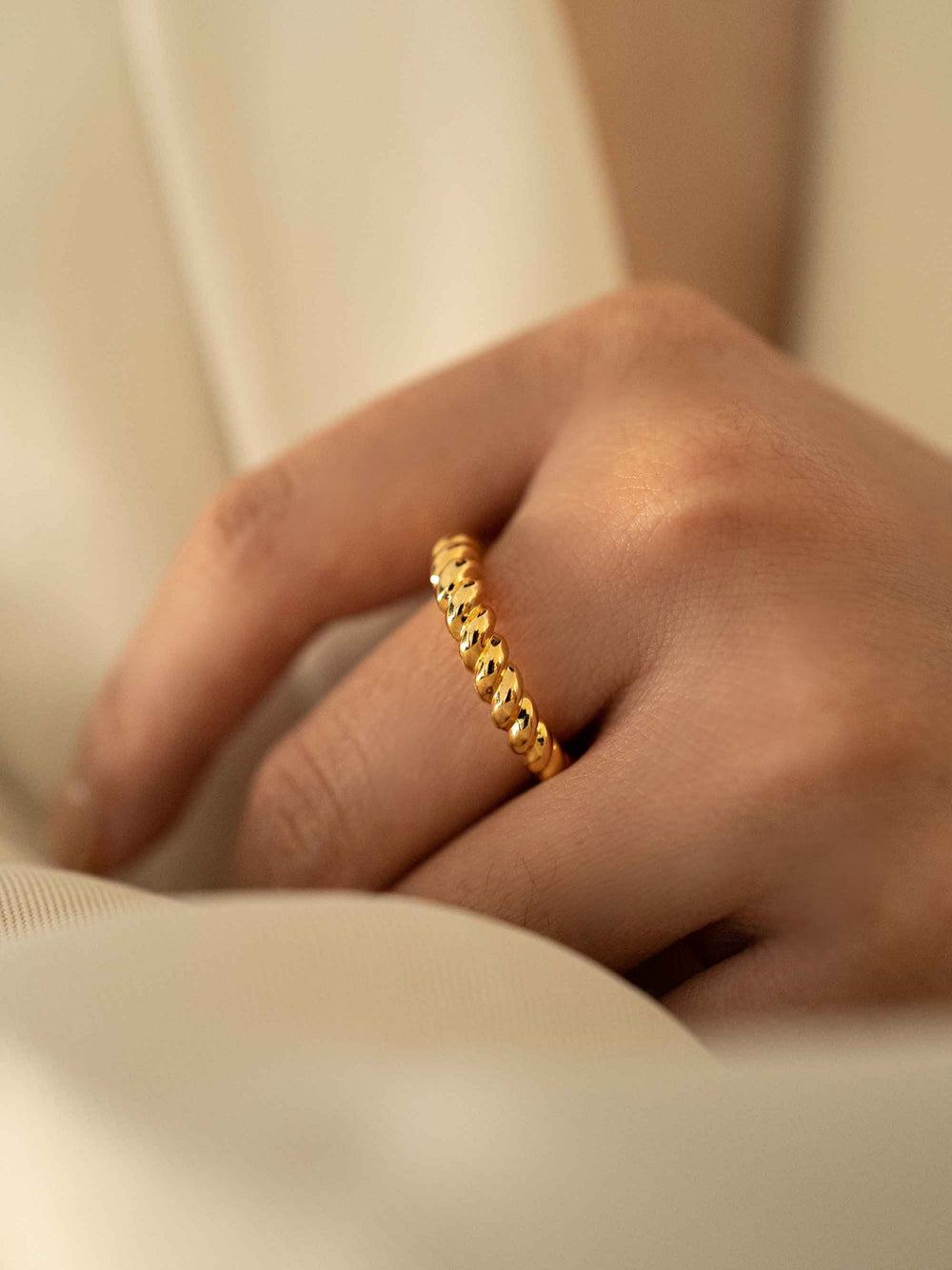 a hand wear A gold twist ring.