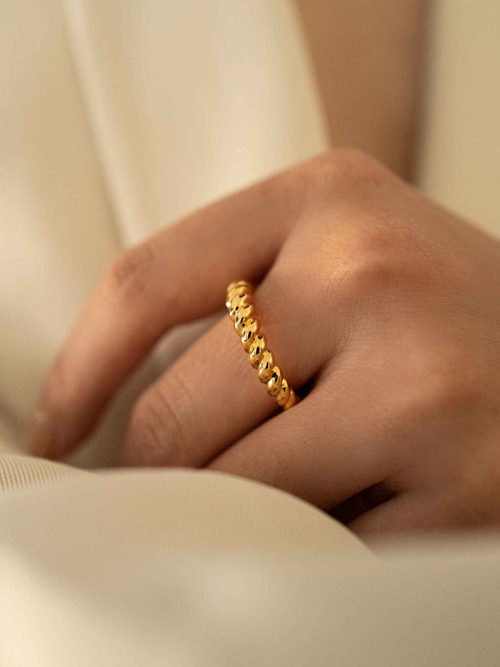 a hand wear A gold twist ring.