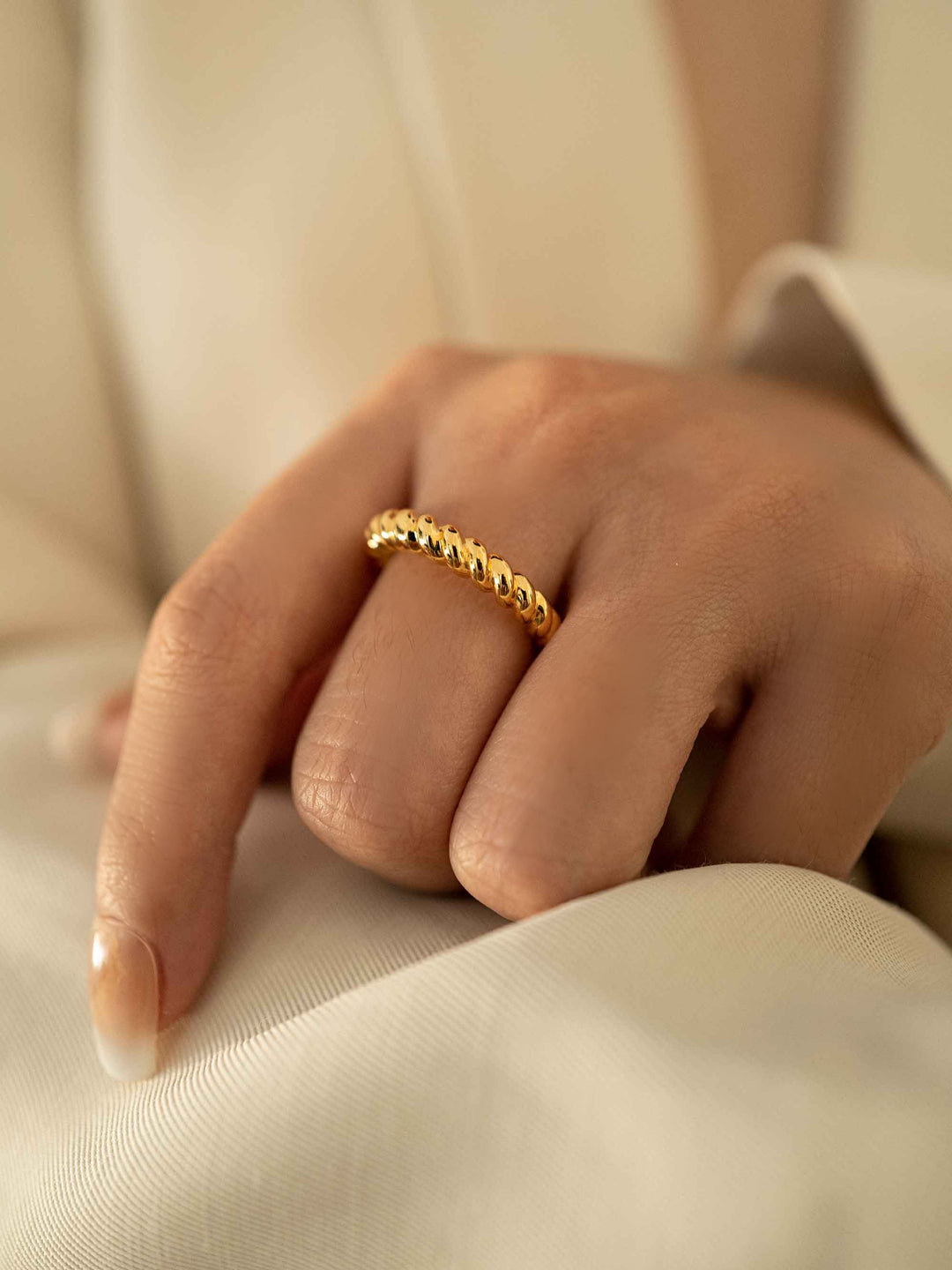 a hand wear A gold twist ring.