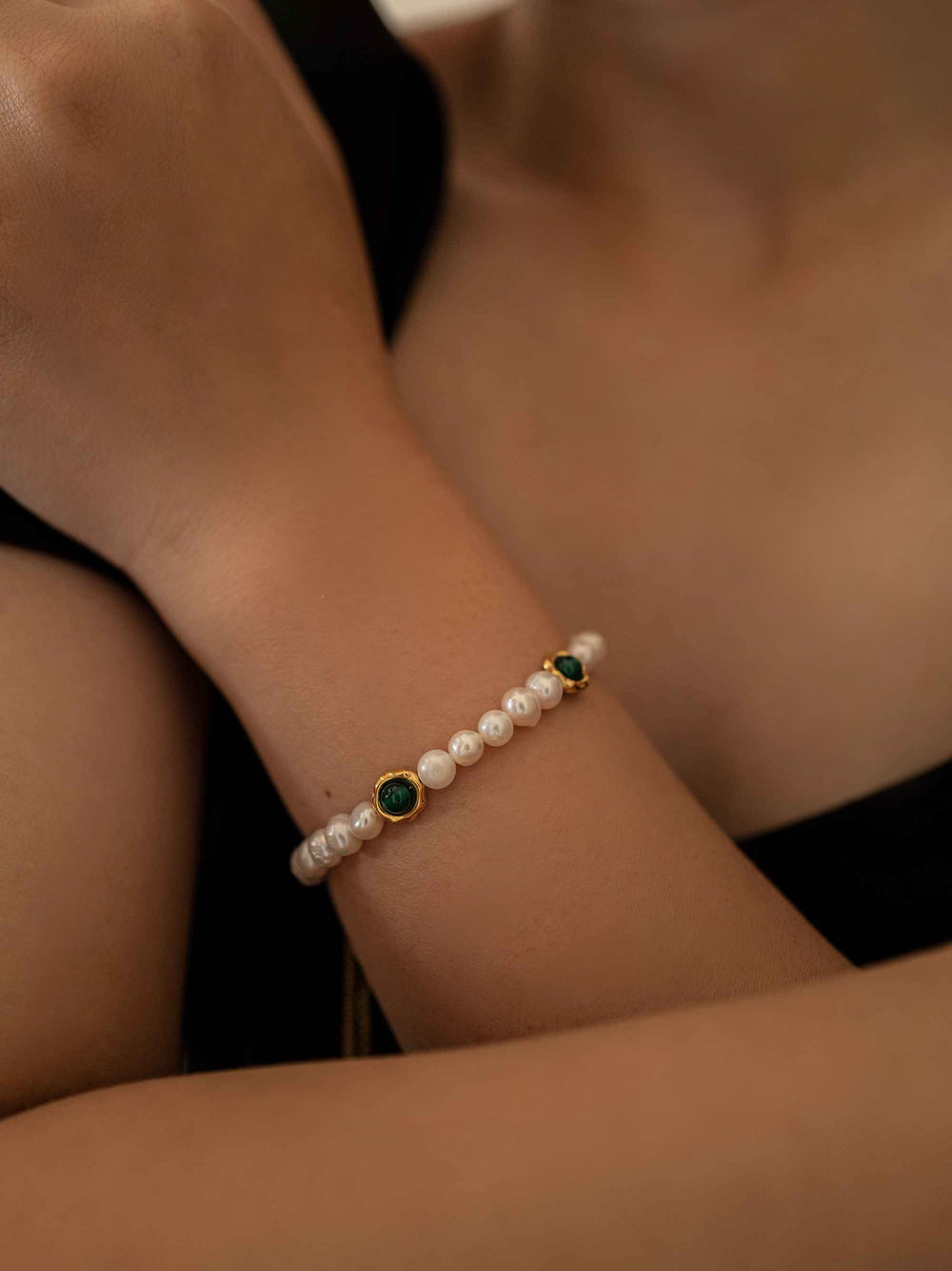 a model wear A bracelet of green stones and cultured pearls with gold