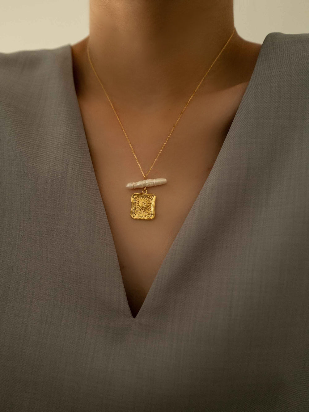 a model wear A gold necklace with square pendants and baroque pearls