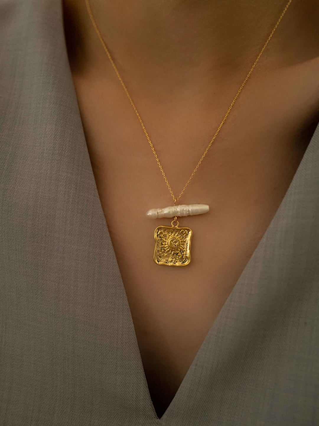 a model wear A gold necklace with square pendants and baroque pearls