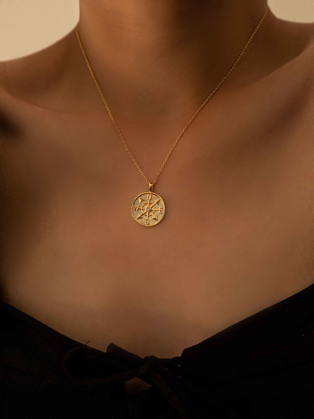 a model wear A gold necklace with a round pendant