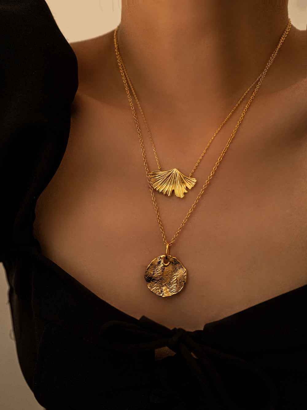 a model wear A gold necklace with a round pendant
