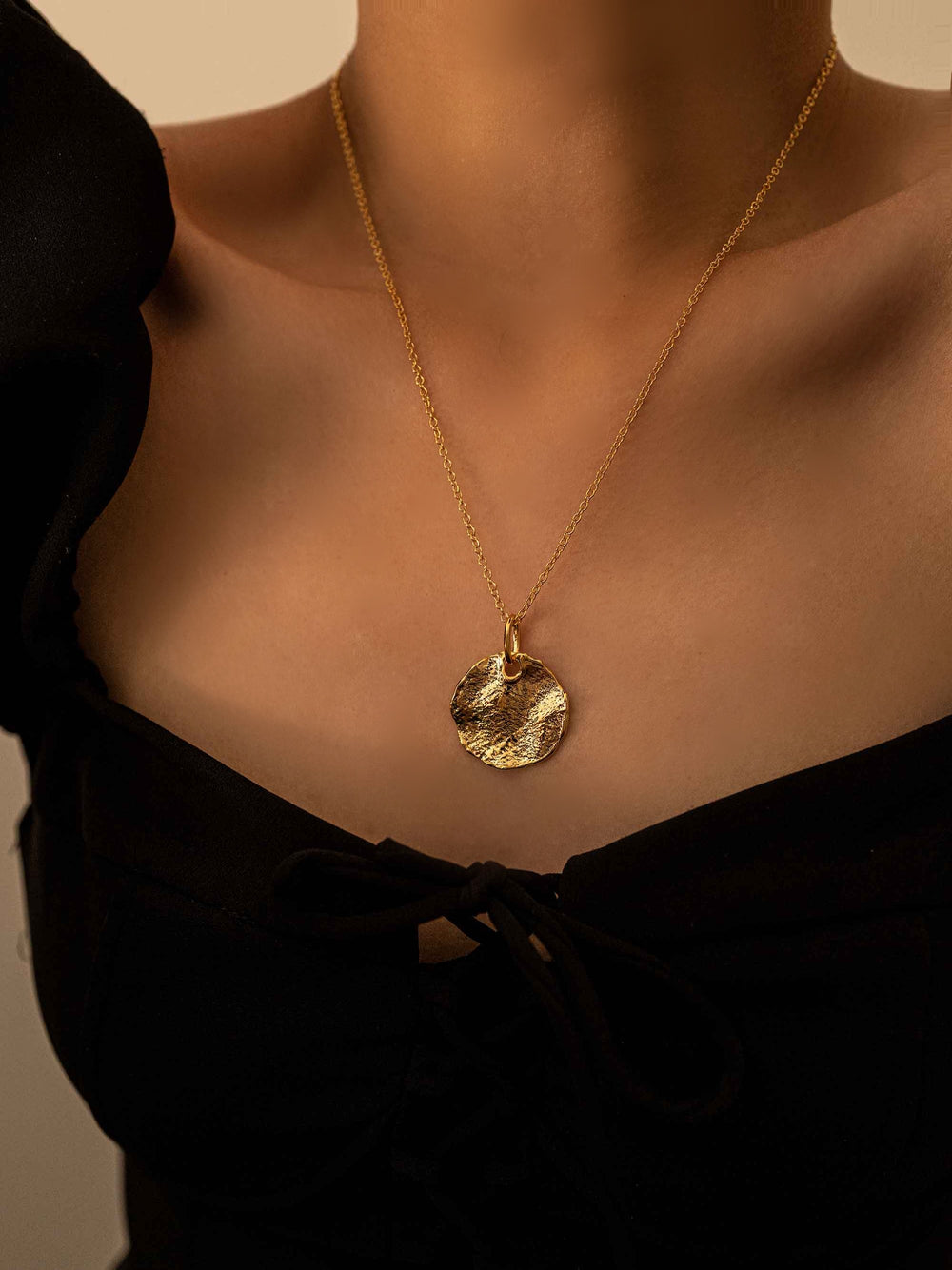 a model wear A gold necklace with a round pendant