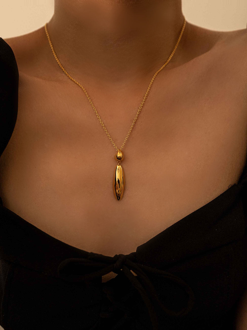 A gold necklace with a simple pendant
