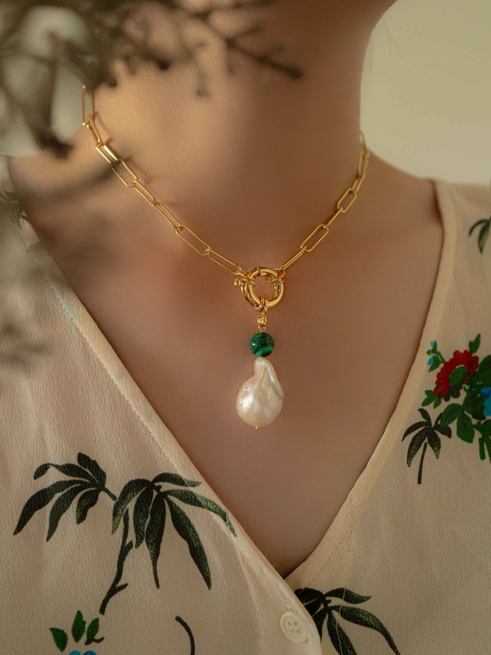 Model with a gold necklace with baroque pearls and malachite