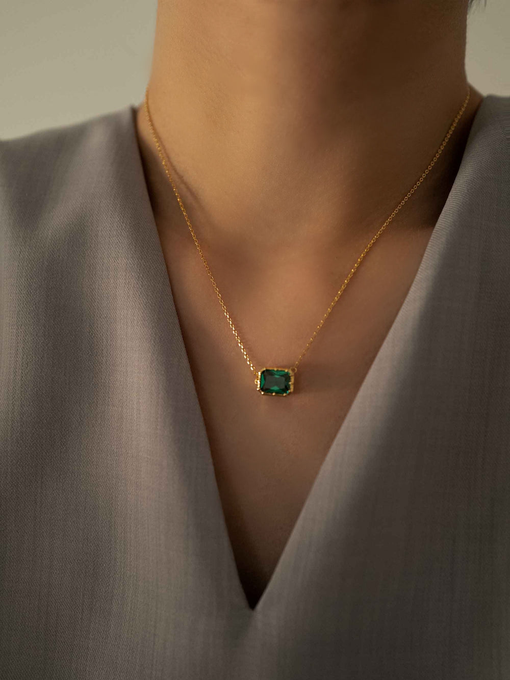 a model wear A green crystal gold necklace