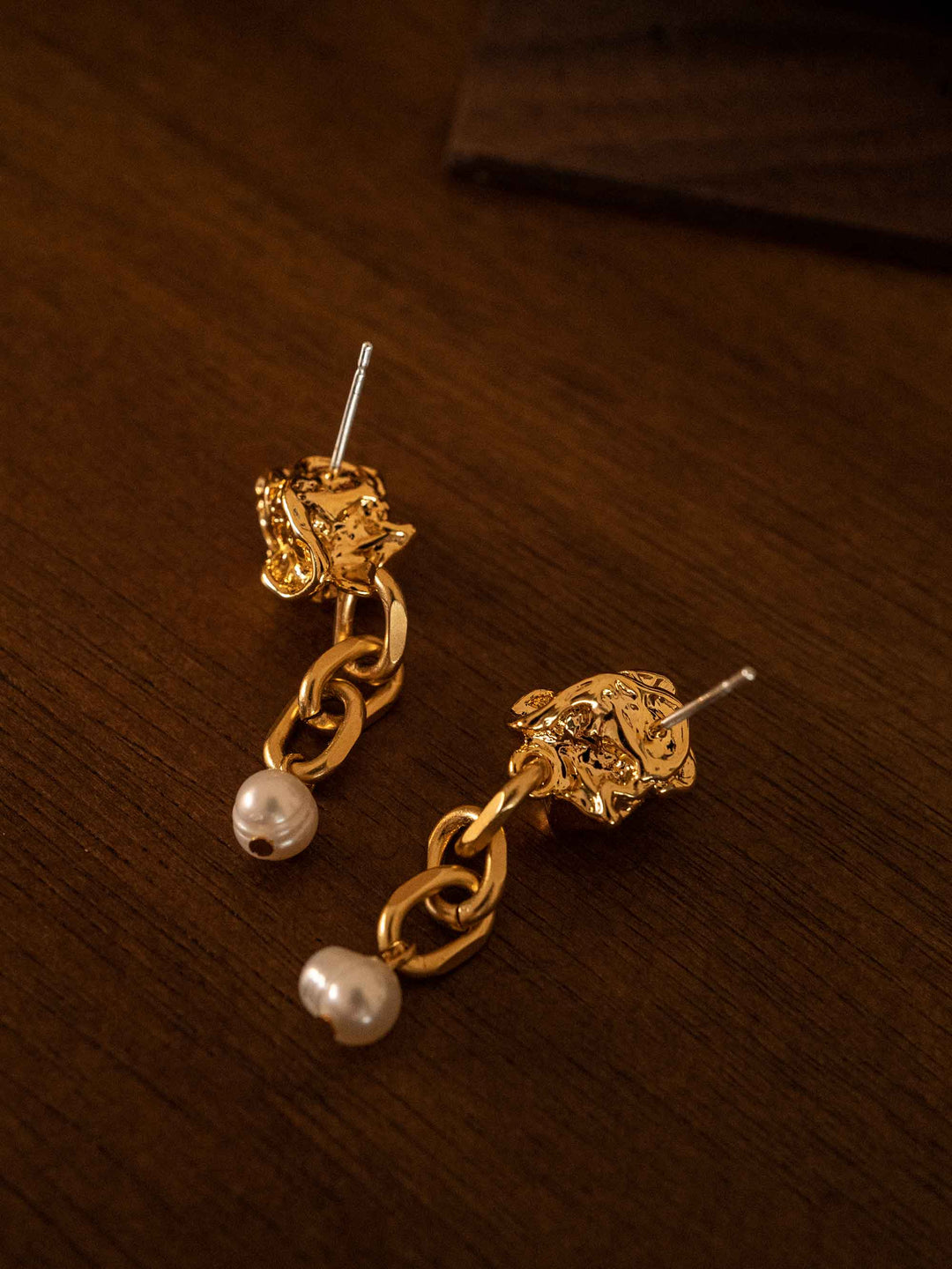 A gold chain earring with cultured pearls dangling from it