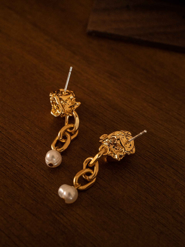 A gold chain earring with cultured pearls dangling from it