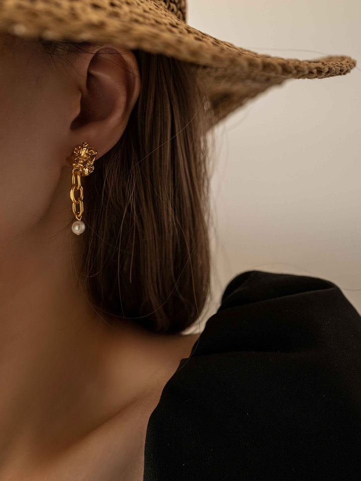 a model wear A gold chain earring with cultured pearls dangling from it