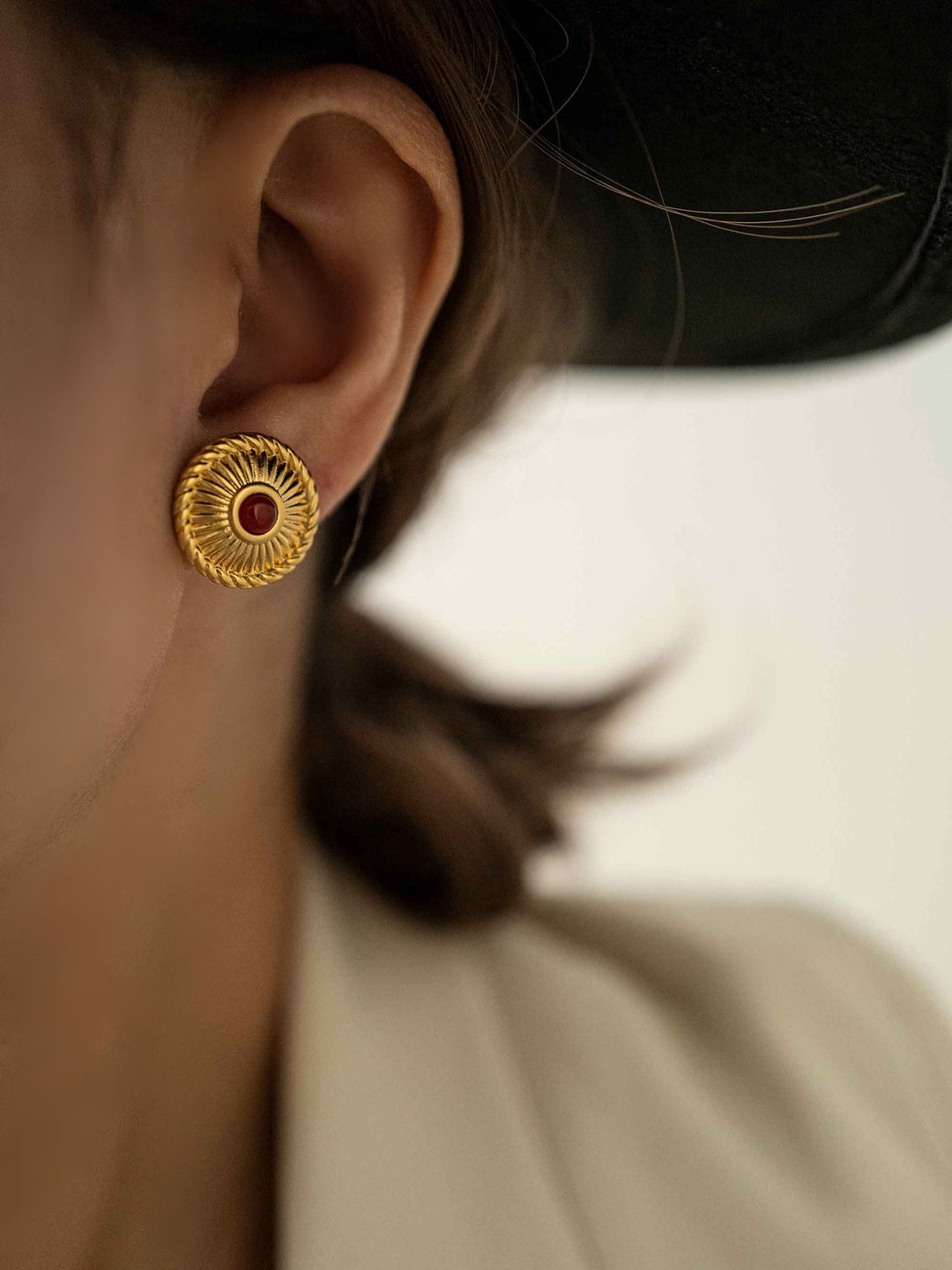 a model wear A golden earring with red crystal agate