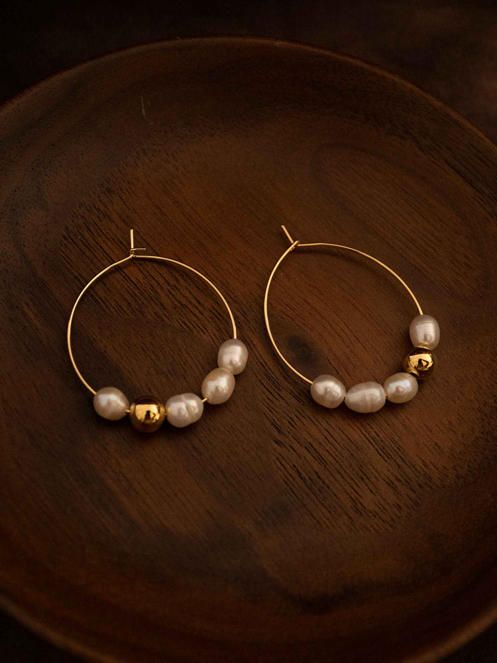 A pair of oval hoop pearl gold earrings