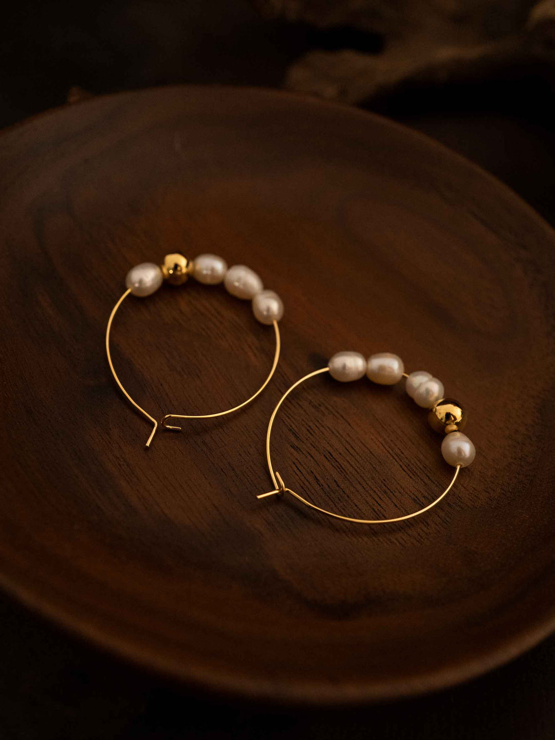 A pair of oval hoop pearl gold earrings