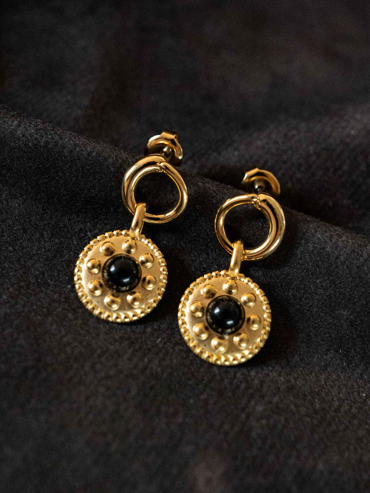 A pair of golden earrings with black crystal onyx