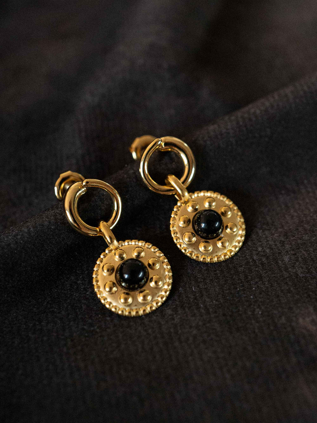 A pair of golden earrings with black crystal onyx