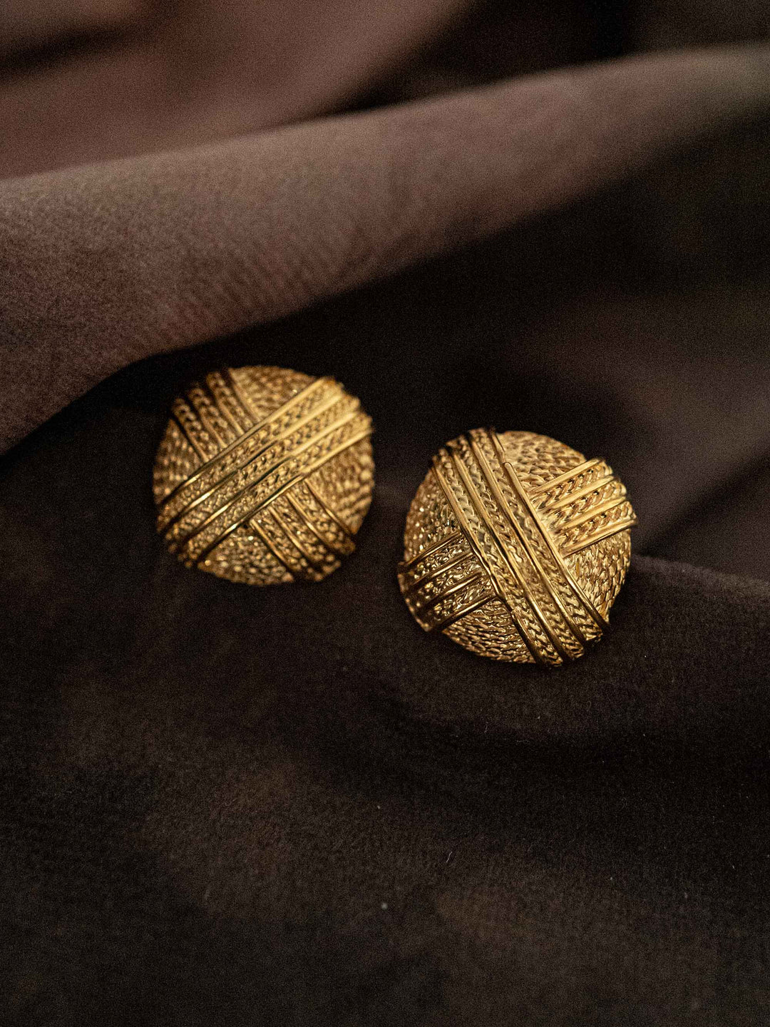 A round gold earring with a criss-cross pattern