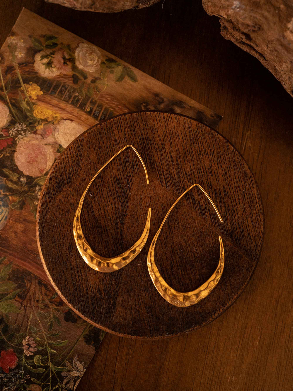 A pair of gold earrings in the shape of a garden hanging basket chair