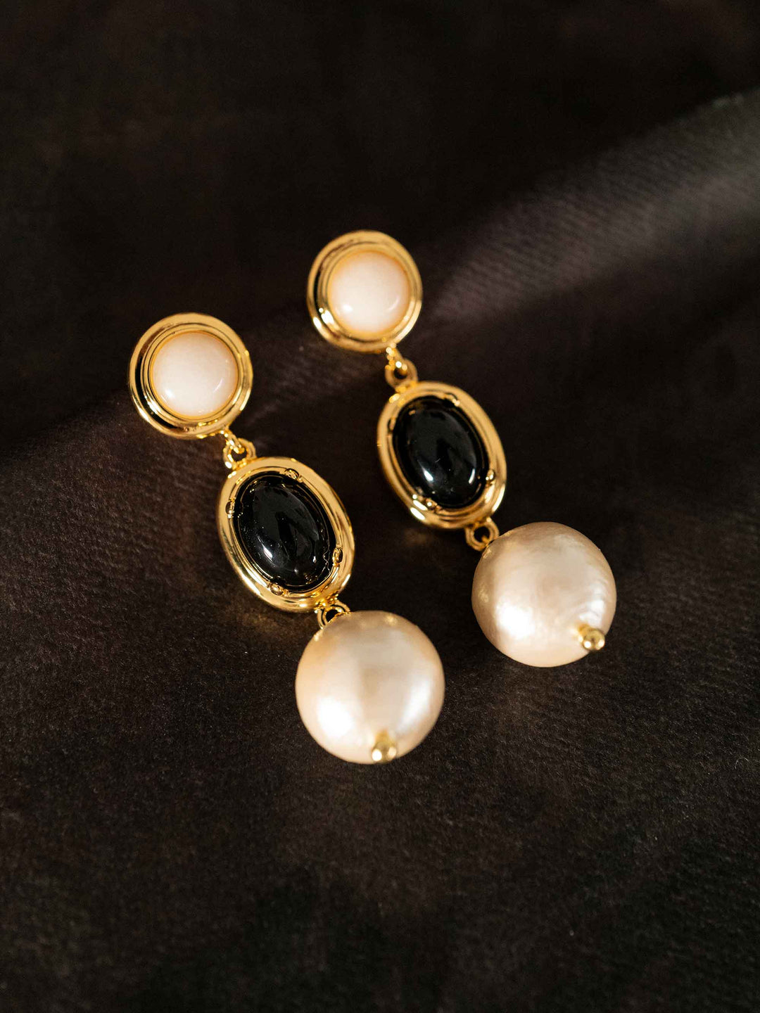 A long earring composed of stones and cotton pearls