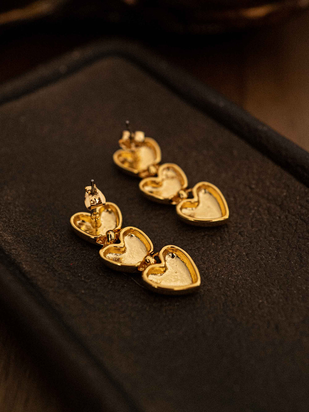 A gold earring with three hearts