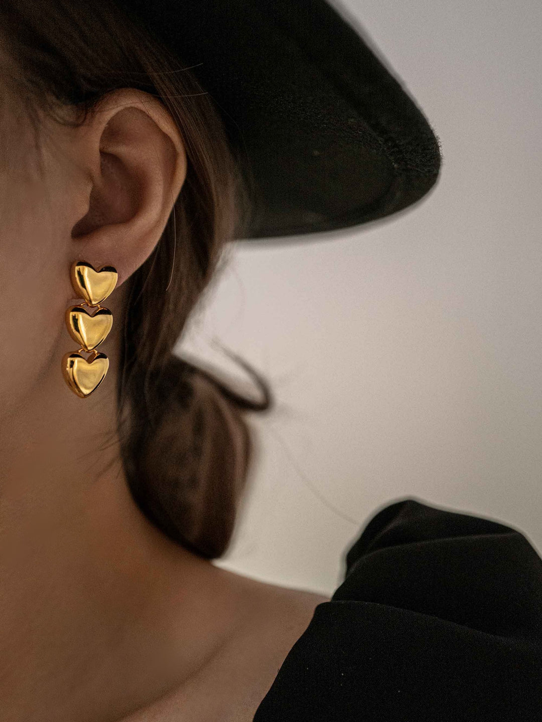 a model wear A gold earring with three hearts