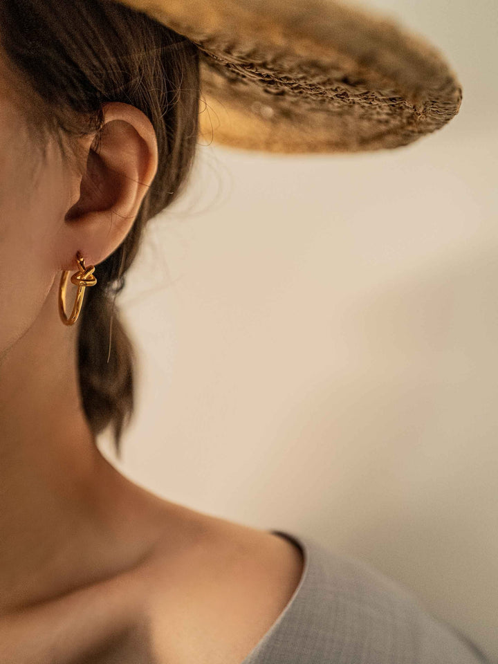 a model wear A hoop of gold earrings with a love knot