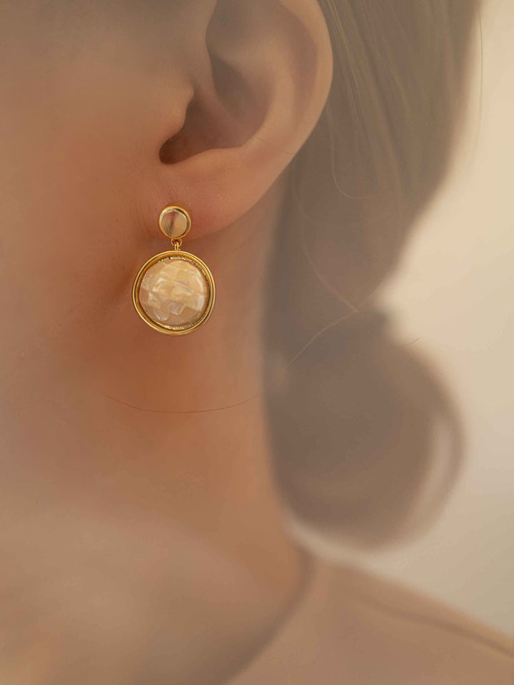 Model with golden abalone shell earrings