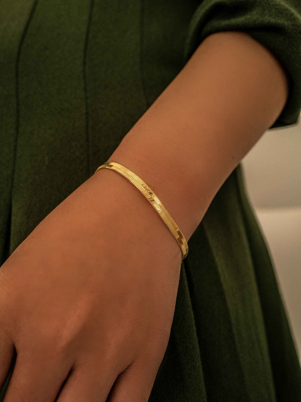 a hand with A gold bracelet in the shape of a snake bone chain