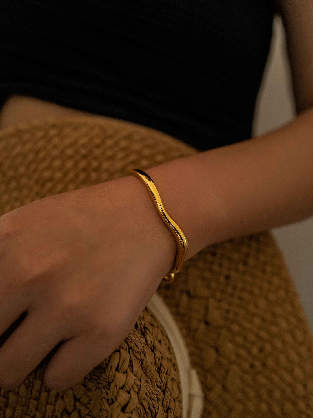 a hand wear a A gold bracelet with a gold hook closure