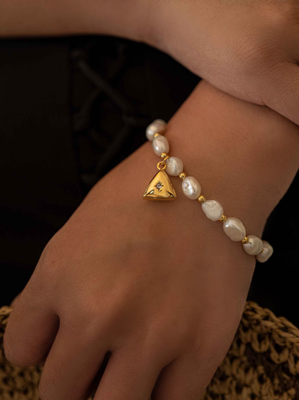 a hand wear A pearl bracelet with a triangular pendant