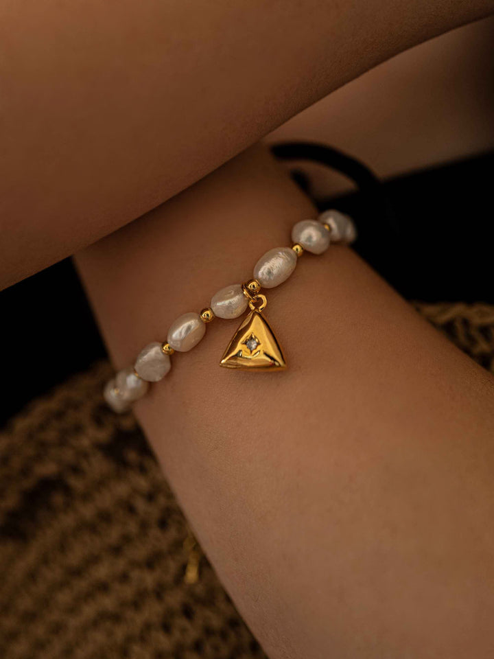 a hand wear A pearl bracelet with a triangular pendant