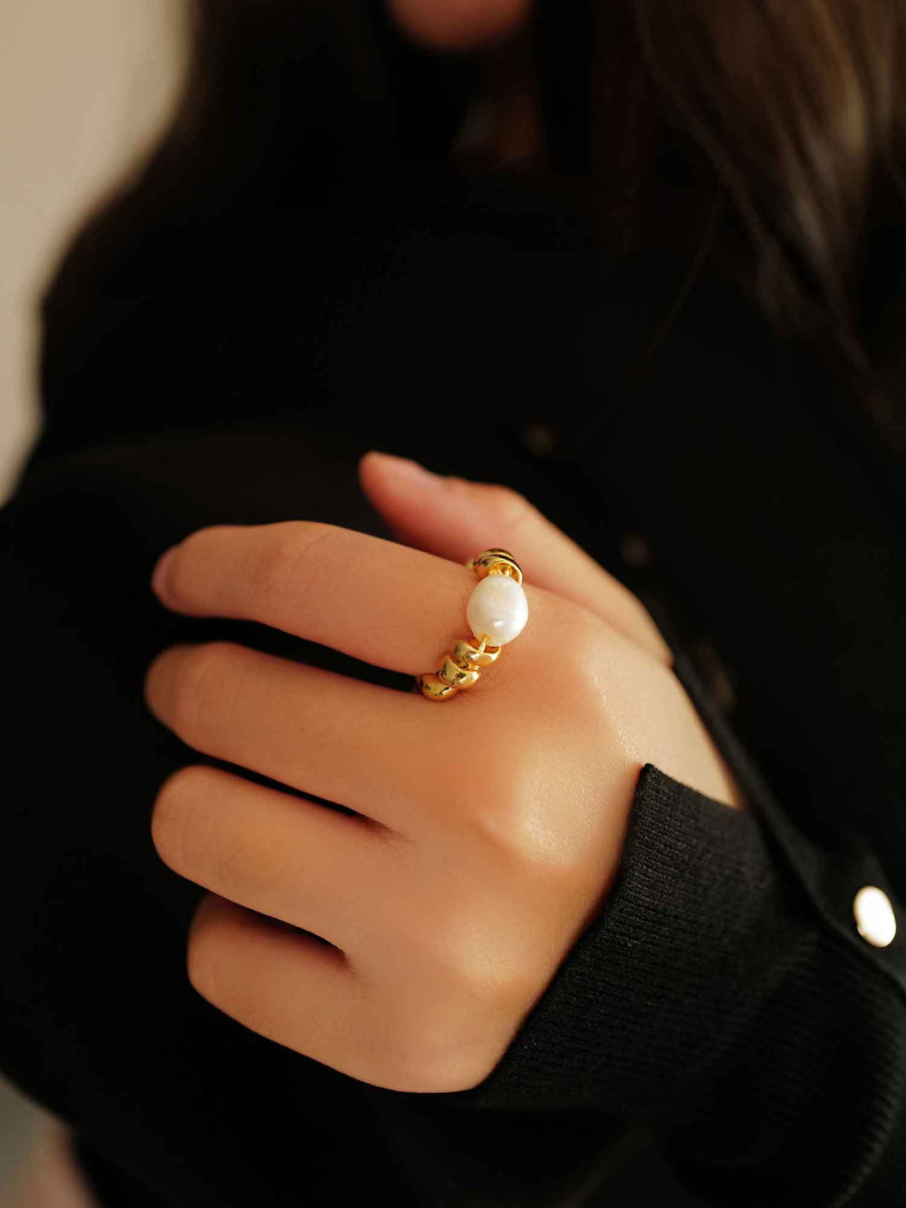 a hand with A gold ring with cultured pearls