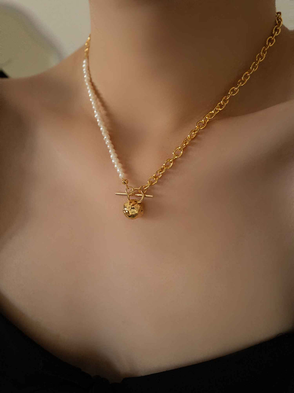 a model wear A golden pearl necklace with a round meteorite pendant