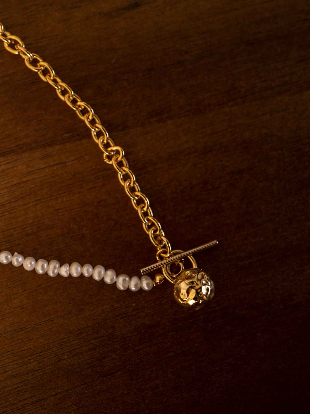 A golden pearl necklace with a round meteorite pendant