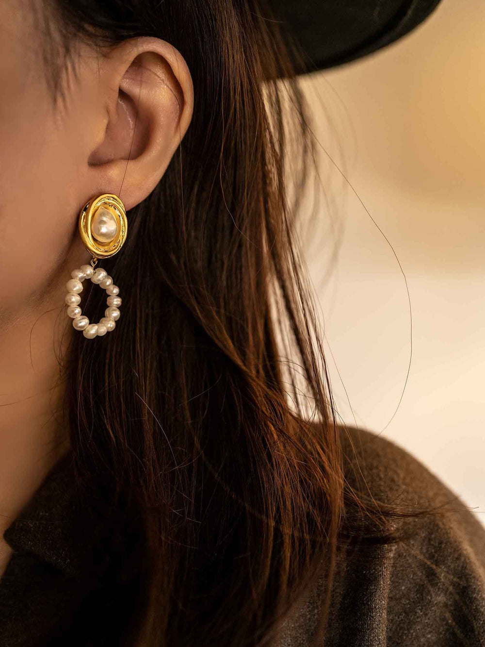 Un modelo con pendientes de perlas de agua dulce redondas doradas