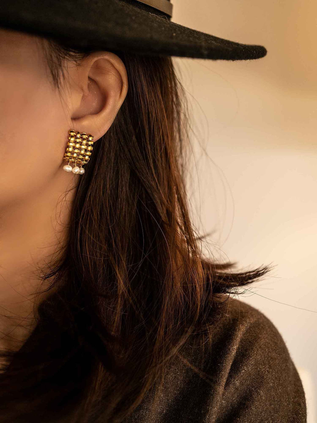 Modelo femenina con pendientes de oro con diseño de bambú tejido