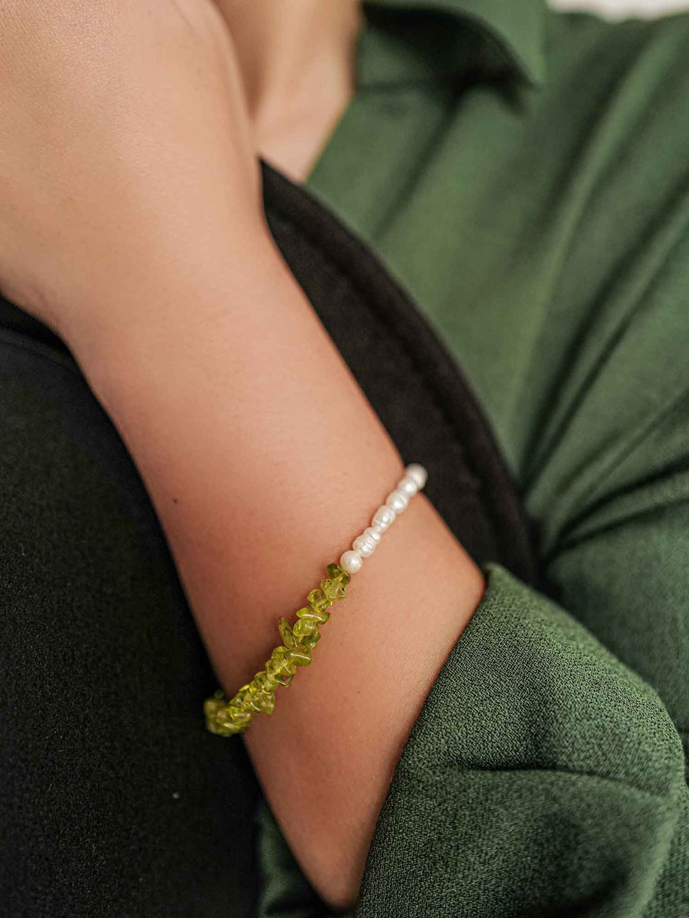 a hand with A bracelet of green stones and pearls